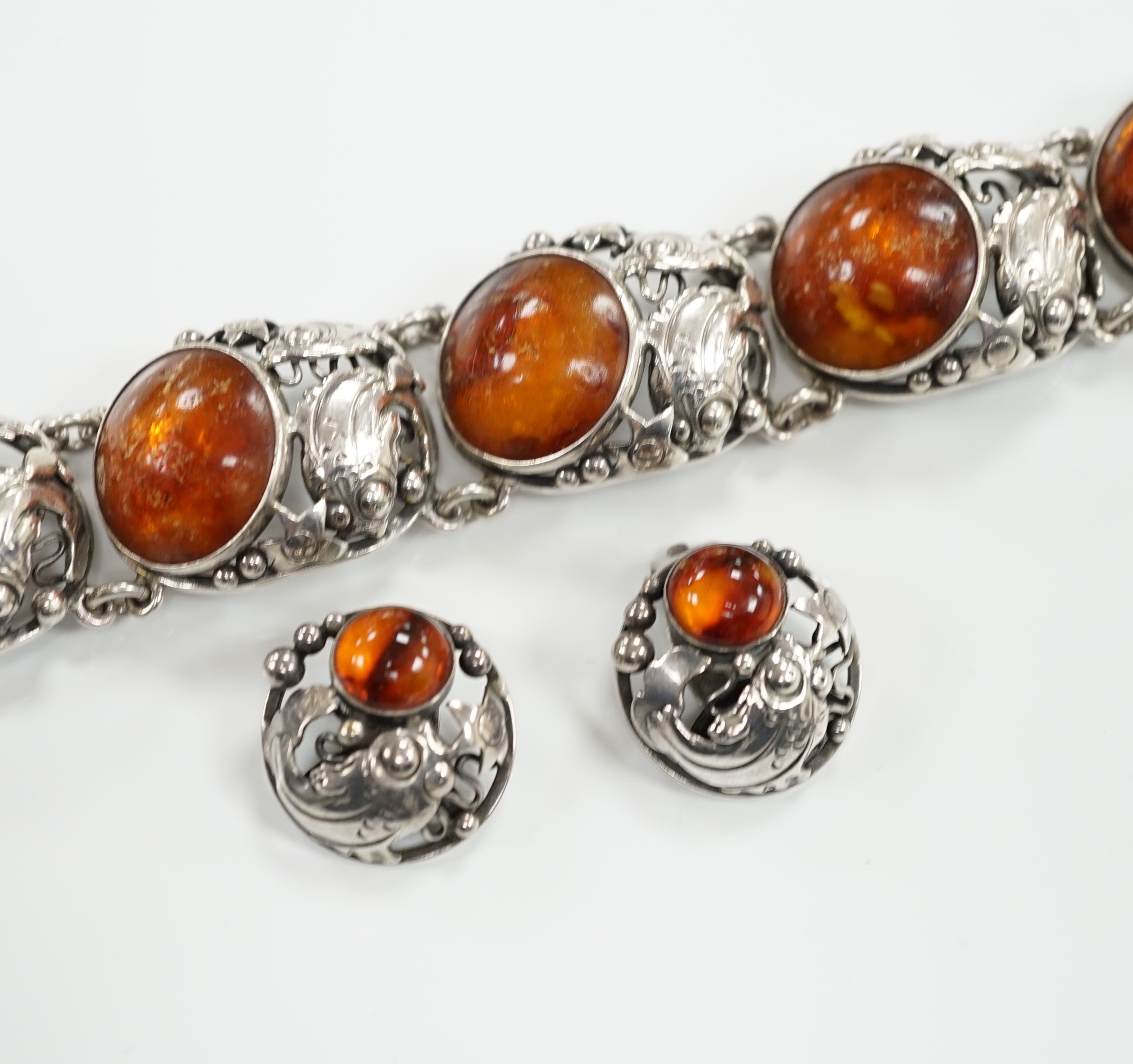 A Danish sterling 925 and amber set bracelet by Niels Erik From, comprising a bracelet 17.5cm and pair of matching circular ear clips, with fish, star and bead decoration.